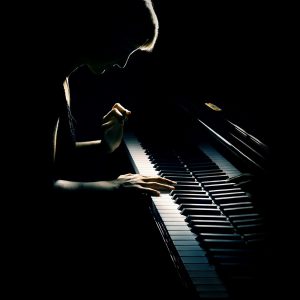 Piano playing pianist concert. Classical music musician player with grand piano in darkness